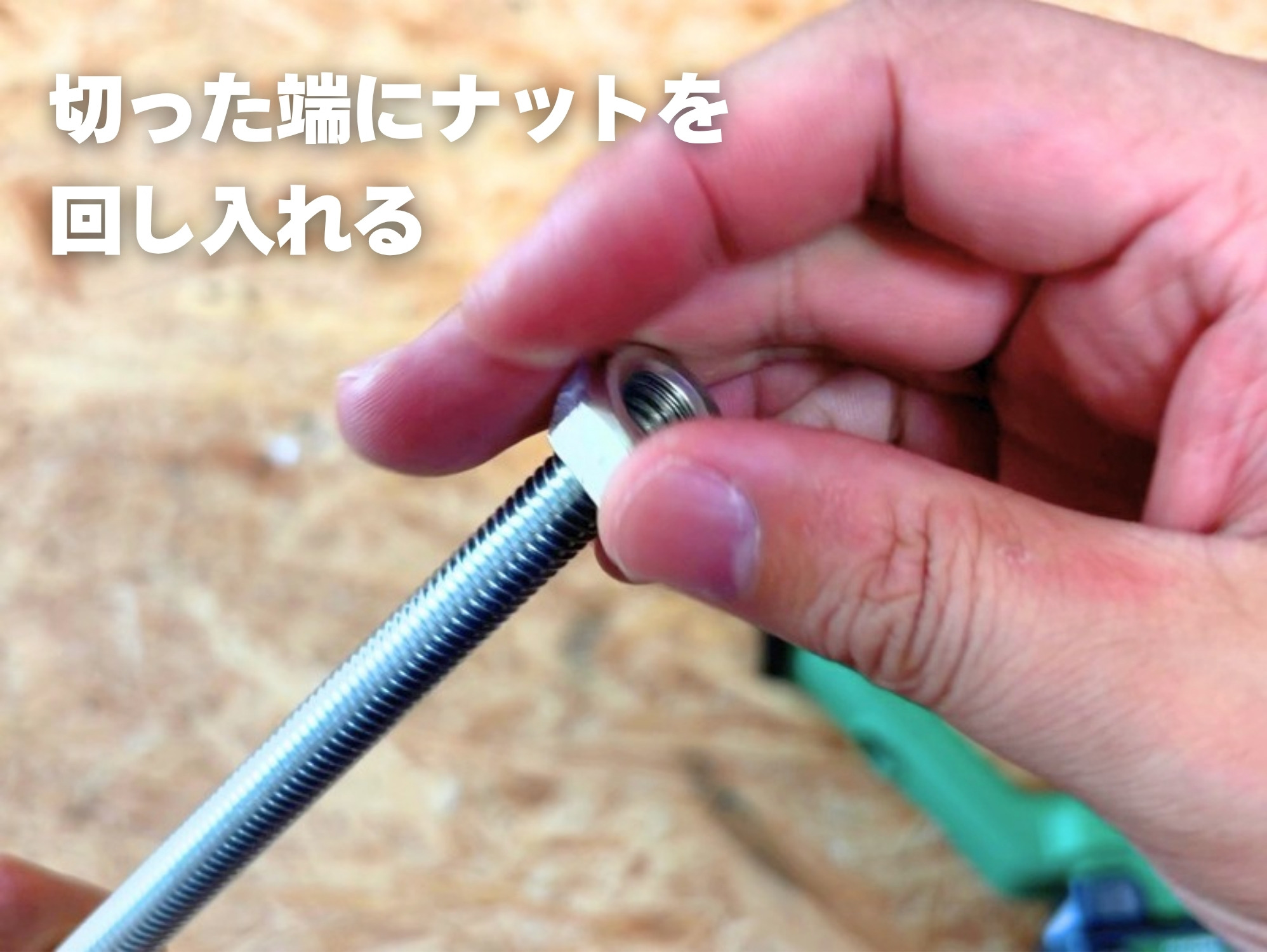 切った全ねじの端にナットを回し入れる手元